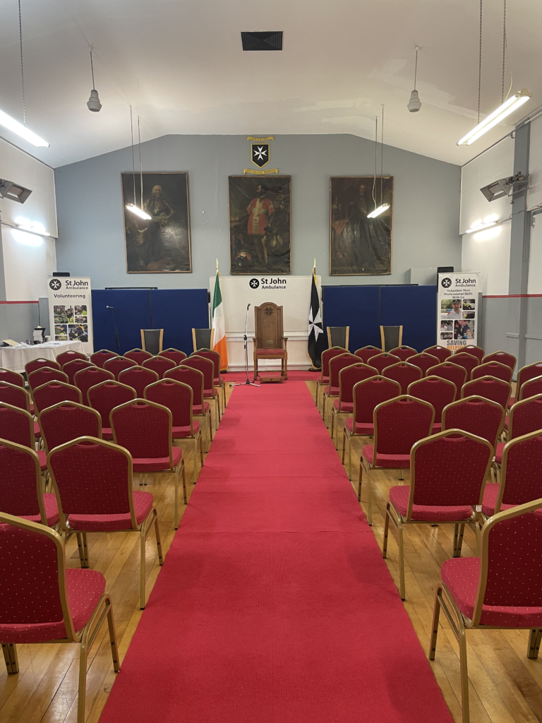 The Overend Hall at SJAI National Headquarters set up for an Awards Ceremony. Rows of chairs with the natioal flag and the St John Ambulance Ireland flag at the front. 
